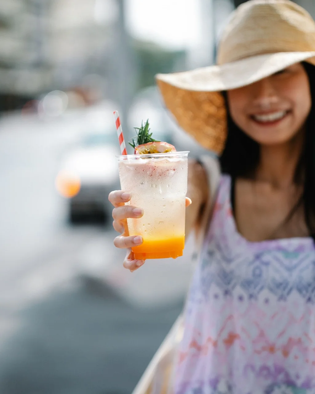 Before: smiling woman holding an iced drink toward the camera